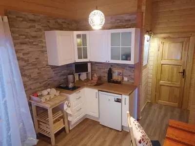 a small kitchen with white cabinets and a table at The Archers House in Viktariškės
