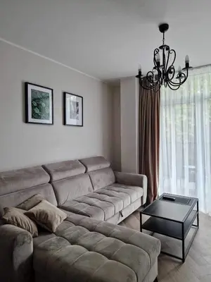 a living room with a couch and a chandelier at Parko nauji apartamentai in Panevėžys