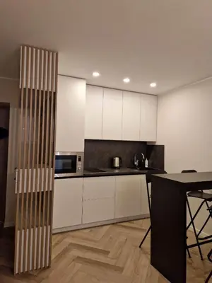 a kitchen with white cabinets and a table at Parko nauji apartamentai in Panevėžys