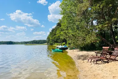 two chairs and a boat on the shore of a lake at Premium Forest Bungalow with Ofuro Tub in Luokesos Sen