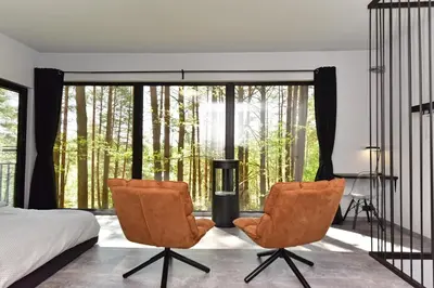 a bedroom with a bed and two chairs in front of a window at Premium Forest Bungalow with Ofuro Tub in Luokesos Sen