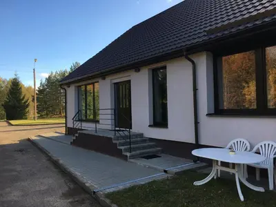 a house with a table and two chairs in front of it at Klykių apartamentai in Klykiai