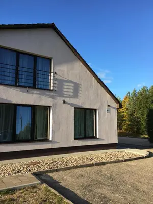 a white house with windows on the side of it at Klykių apartamentai in Klykiai