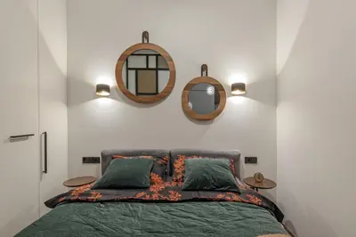 a bedroom with a bed with two mirrors on the wall at IVIS House - Stylish and Original Apartment in Vilnius Old Town in Vilnius