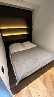 a small bed in a small room with wooden floors at J. Ralio apartamentai in Vilnius