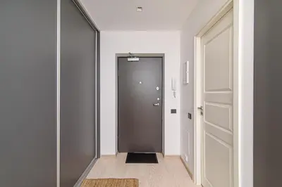 a hallway with a black door and a hallway with a rug at Modern Apartment Next to Ozas park by URBAN RENT in Vilnius