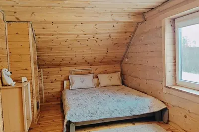 a bedroom with a bed in a log cabin at Padvarių sodyba ant tvenkinio kranto su pirtimi in Šiupieniai