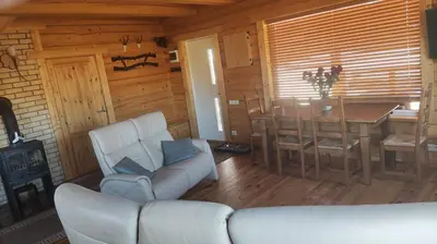 a living room with a couch and a table in a cabin at Padvarių sodyba ant tvenkinio kranto su pirtimi in Šiupieniai