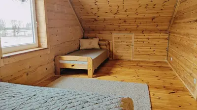 a room with a bed and a window in a log cabin at Padvarių sodyba ant tvenkinio kranto su pirtimi in Šiupieniai