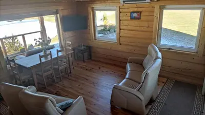 a living room with chairs and a table in a cabin at Padvarių sodyba ant tvenkinio kranto su pirtimi in Šiupieniai