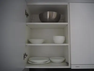 a white cabinet with bowls and a toilet in it at Sunny apartment with lake and forest view in Visaginas