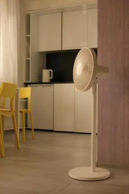 a white fan in a room with a kitchen at Sunny apartment with lake and forest view in Visaginas