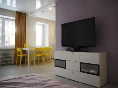 a living room with a television on a white dresser at Sunny apartment with lake and forest view in Visaginas