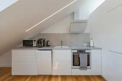 a kitchen with white cabinets and a sink at White 1 BD Old Town Apartment by Hostlovers in Kaunas