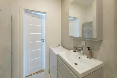 a white bathroom with a sink and a mirror at White 1 BD Old Town Apartment by Hostlovers in Kaunas