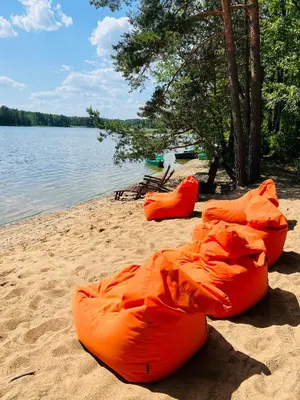 a group of orange tubes on a beach next to a lake at Premium Forest Bungalow with HOT TUB in Ažuluokesa