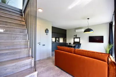 a living room with an orange couch and a kitchen at Premium Forest Bungalow with HOT TUB in Ažuluokesa