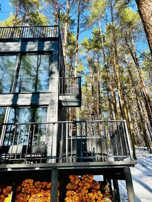 a house with a balcony and a pile of leaves at Premium Forest Bungalow with HOT TUB in Ažuluokesa