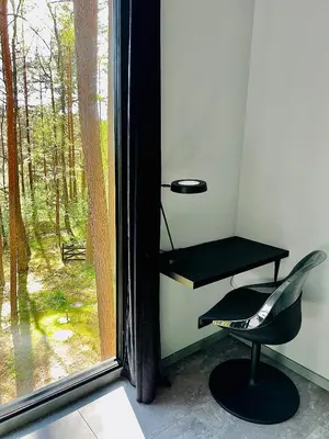 a black desk and a chair next to a window at Premium Forest Bungalow with HOT TUB in Ažuluokesa
