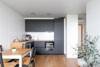 a kitchen with black cabinets and a wooden table at Cozy Apartment with panoramic view in Anykščiai