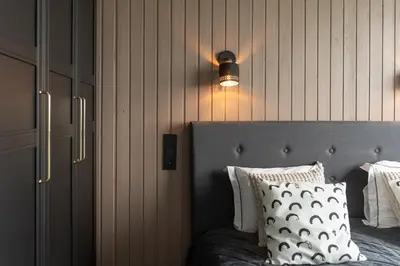 a bedroom with a bed with a light on the wall at Cozy Apartment with panoramic view in Anykščiai