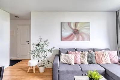 a living room with a gray couch with pink pillows at Cozy Apartment with panoramic view in Anykščiai