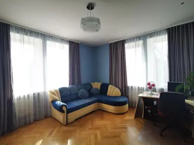 a living room with a blue couch in front of windows at Spacious Apartment with free parking in Kaunas in Kaunas