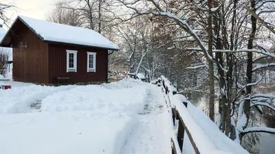a house covered in snow next to a fence at Namelis Šiaurėje in Kaltanėnai