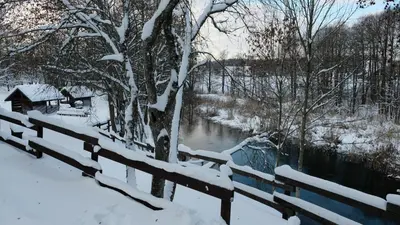 a fence covered in snow next to a river at Namelis Šiaurėje in Kaltanėnai