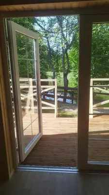 an open door to a deck with a tree at Namelis Šiaurėje in Kaltanėnai