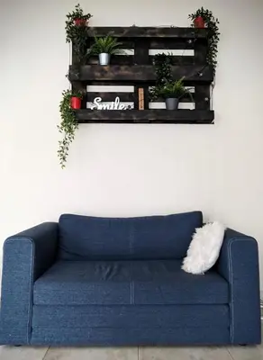 a blue couch in a living room with a shelf with plants at Baltamiškio slėnis in Baltamiškis