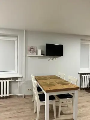 a dining room table with chairs and a television on the wall at Saulėti apartamentai Trakuose/Sunny apartment in Trakai in Trakai