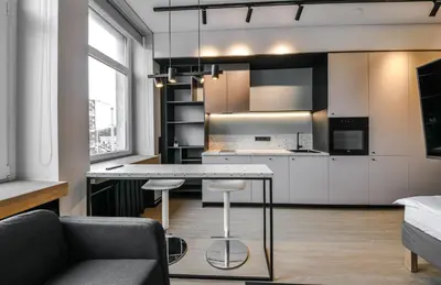 a kitchen with white cabinets and a table with stools at Apartments in Vilnius in Vilnius
