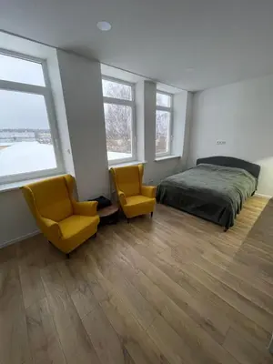 a bedroom with a bed and two yellow chairs at 30 Airport apartment in Vilnius