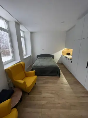 a bedroom with a bed and a yellow chair at 30 Airport apartment in Vilnius
