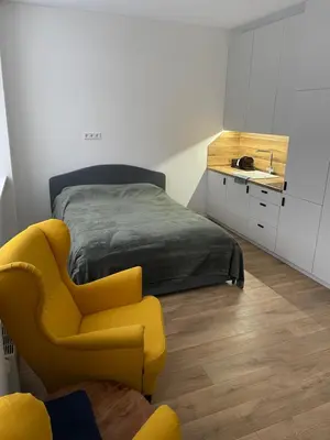 a bedroom with a bed and a yellow chair at 30 Airport apartment in Vilnius