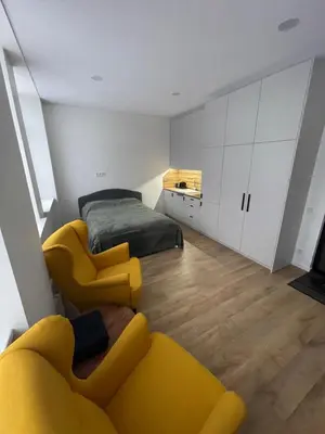 a living room with a yellow couch and a bed at 30 Airport apartment in Vilnius