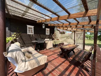 a patio with a wooden pergola and a table at Villa Arjola in Kaltanėnai
