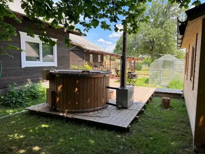 a hot tub on a deck next to a house at Villa Arjola in Kaltanėnai