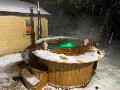 two people in a hot tub in the snow at Villa Arjola in Kaltanėnai