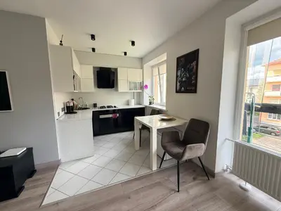 a white kitchen with a table and a chair at Topoliai Apartament Self check -in in Panevėžys