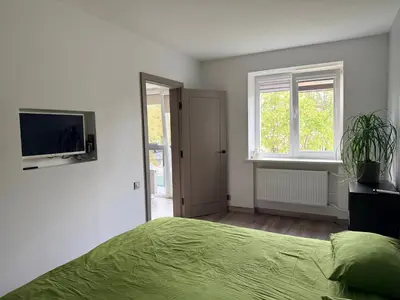 a bedroom with a green bed and a television at Topoliai Apartament Self check -in in Panevėžys