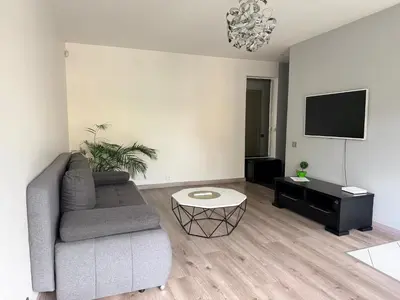 a living room with a couch and a flat screen tv at Topoliai Apartament Self check -in in Panevėžys