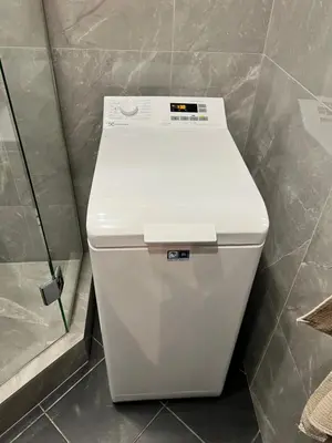 a white toilet in a bathroom next to a shower at Topoliai Apartament Self check -in in Panevėžys