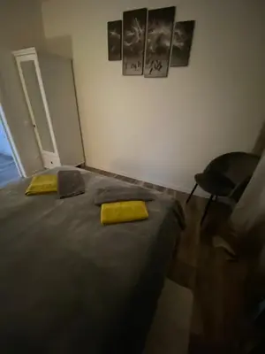 a bedroom with a bed with a yellow blanket and a chair at Trumpalaikė Nuoma-Apgyvendinimas in Rokiškis