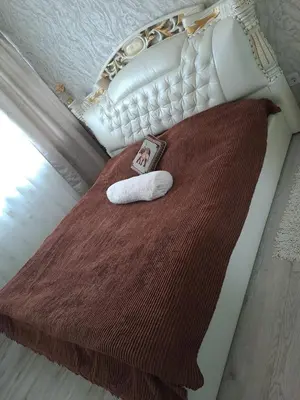 a bed with a blanket and two towels on it at Naujai įrengtas 2-jų kambarių butas in Šiauliai