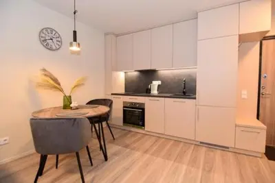 a kitchen with a table and a clock on the wall at Naujai įrengtas 2-jų kambarių butas in Šiauliai