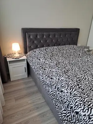 a bedroom with a black and white bed with a lamp at Naujai įrengtas 2-jų kambarių butas in Šiauliai