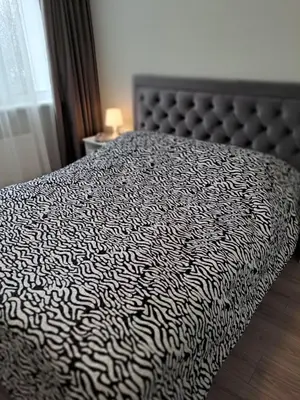 a bed with a black and white comforter in a bedroom at Naujai įrengtas 2-jų kambarių butas in Šiauliai