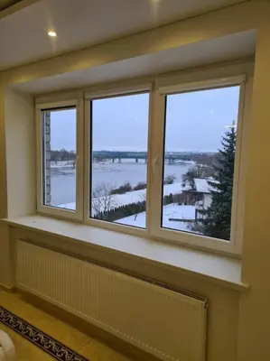 a room with three windows with a view of the water at River view appartment in Kaunas in Kaunas